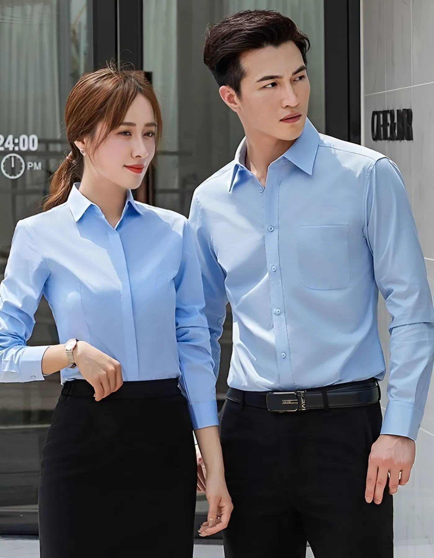 May đồng phục công sở TPHCM: bộ sơ mi - chân váy - vest cho doanh nghiệp 7 may đồng phục công sở TPHCM — đôi nam nữ nhân viên sơ mi xanh nhạt trước tòa nhà văn phòng
